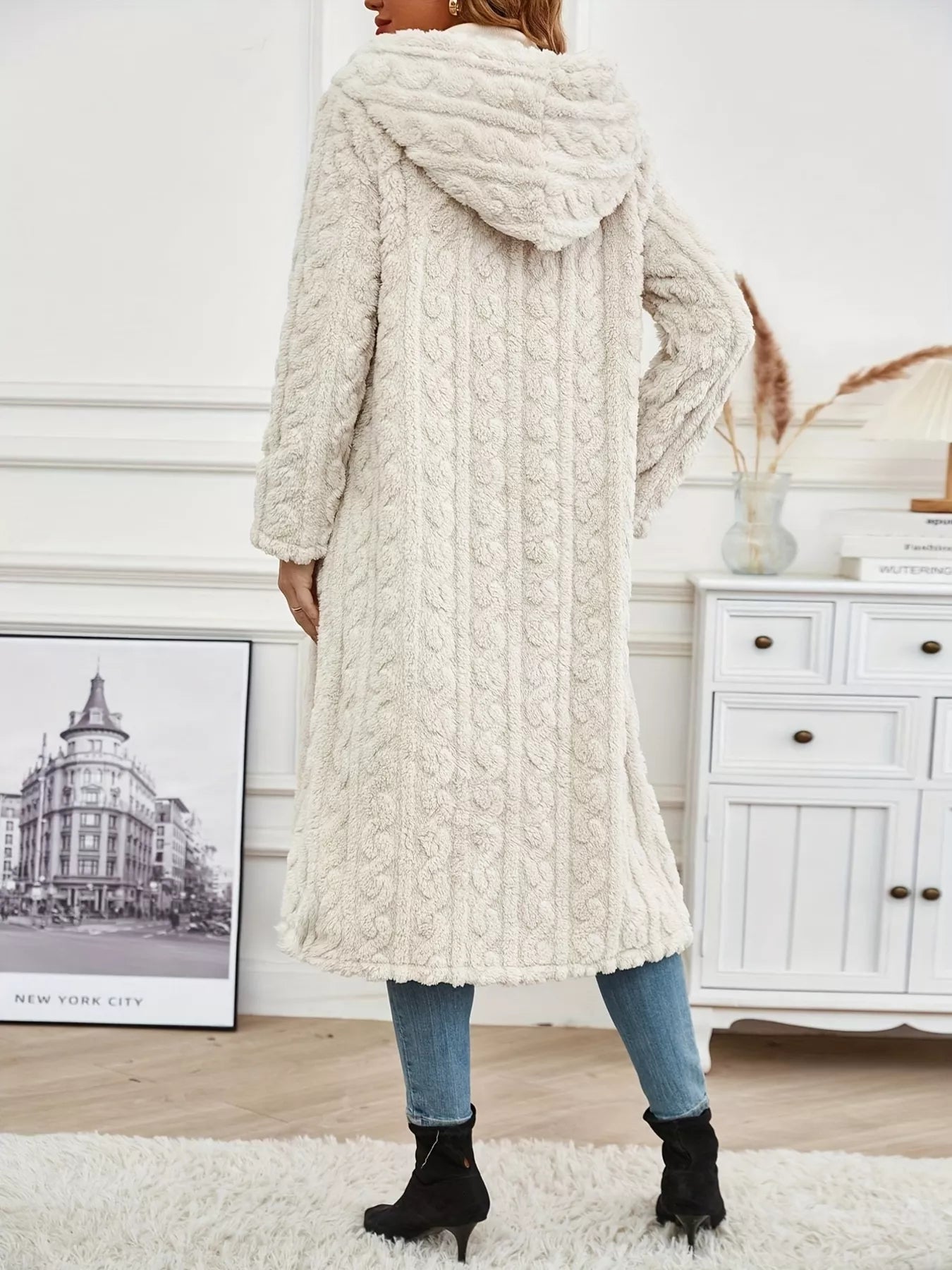 Woman wearing a Sherpa longline hooded coat in cream, showcasing thick texture and cozy design from the back.