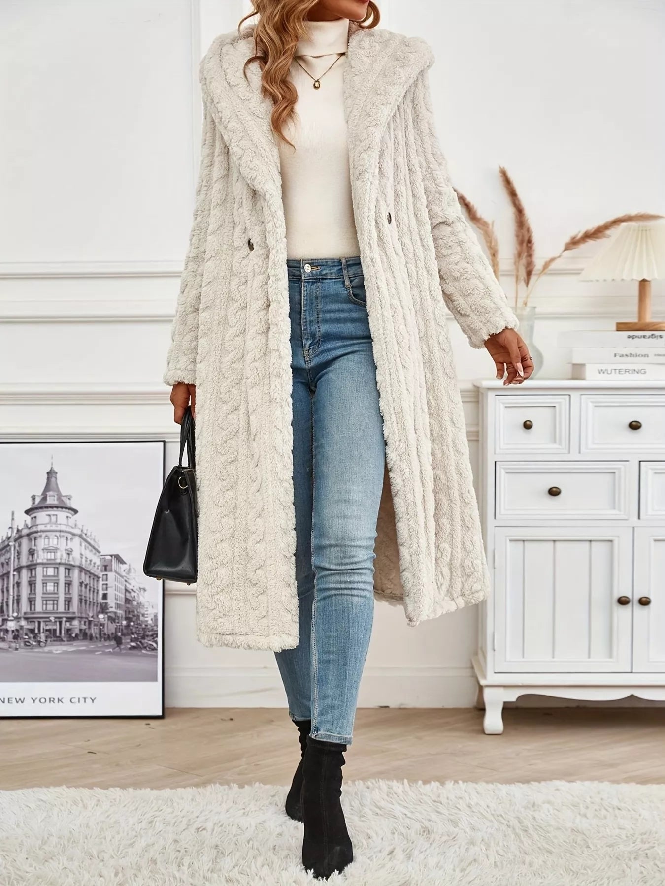 Woman wearing a Sherpa longline hooded coat over a sweater and skinny jeans, showcasing a stylish winter look.