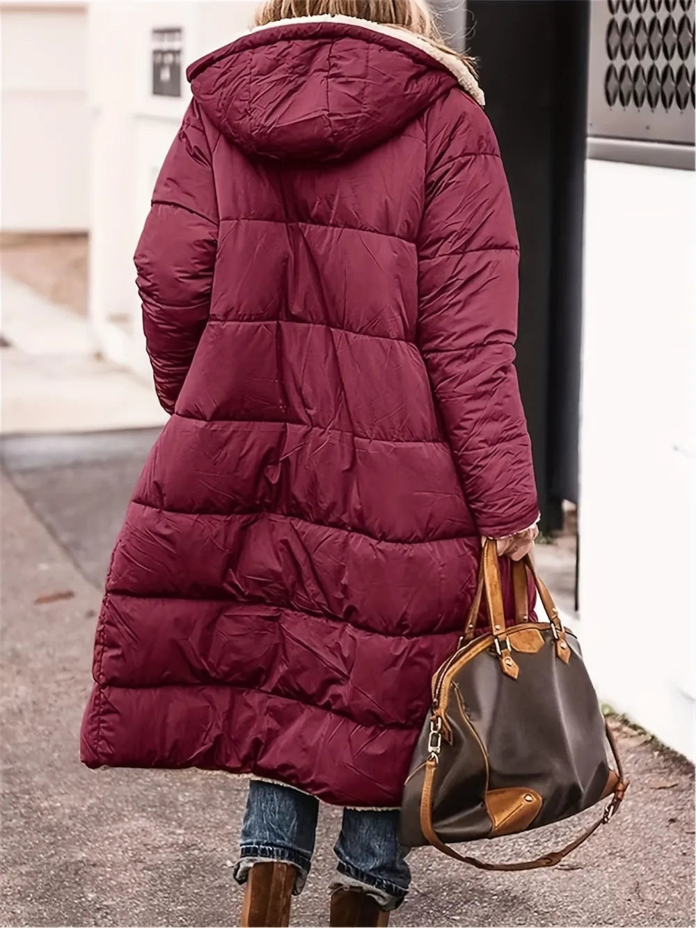 Full size burgundy zip up Sherpa hooded coat, featuring a cozy design, paired with a stylish handbag.