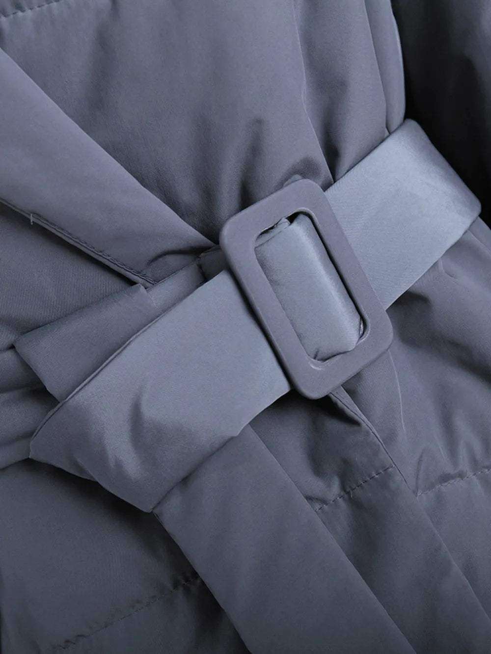 Close-up of a belt on a puffer long sleeve winter coat, showcasing the stylish buckle design.