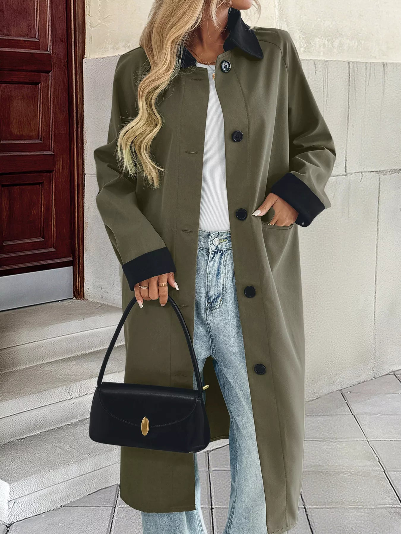 Woman wearing a contrast collar button-up coat with pockets, styled with jeans and a handbag.