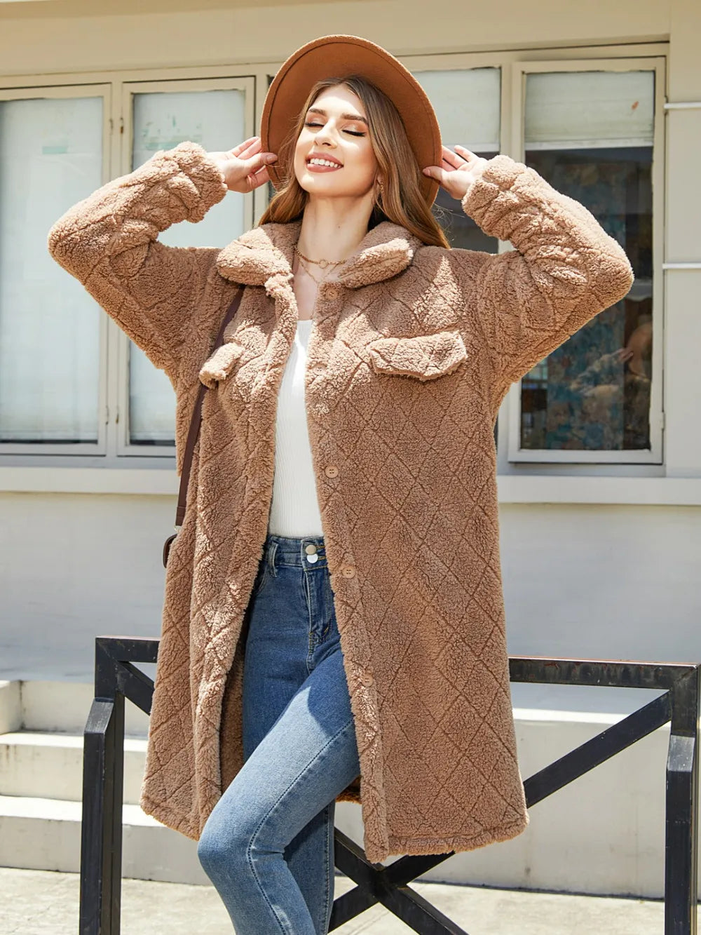 Smiling woman in a cozy beige button-up coat with pockets, enjoying a sunny day outdoors.