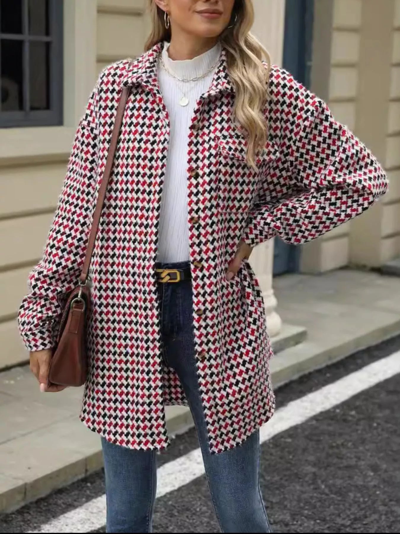 Model wearing a houndstooth button-up long sleeve coat over a white top, styled with blue jeans and a brown bag.