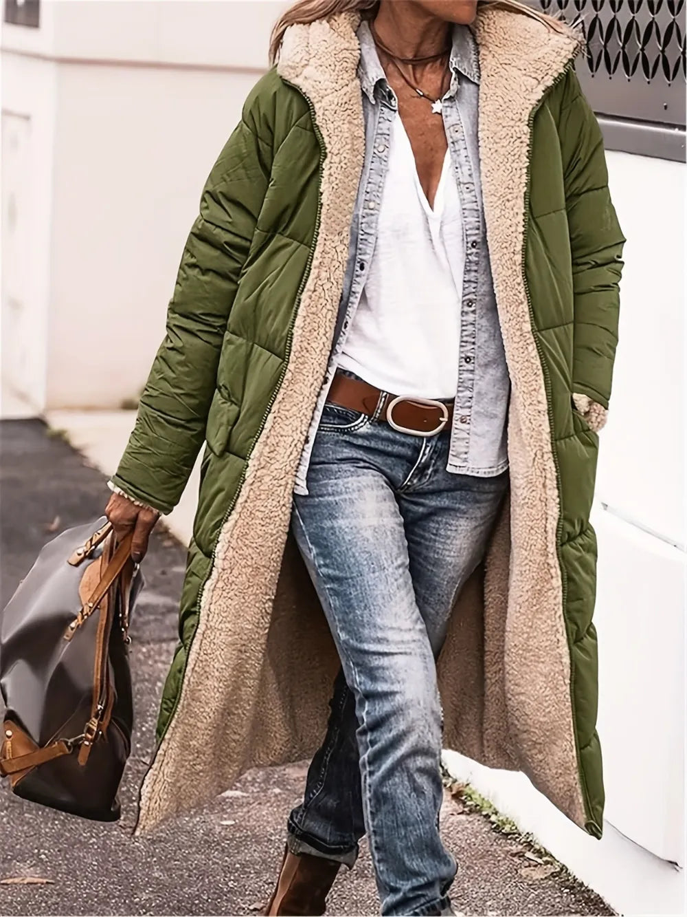 Woman wearing a green sherpa-lined full length coat over casual denim outfit, perfect for stylish winter warmth.
