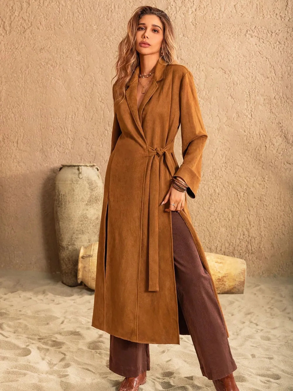 Slit tied collared neck longline coat in brown, styled with matching pants, set against a sandy backdrop.