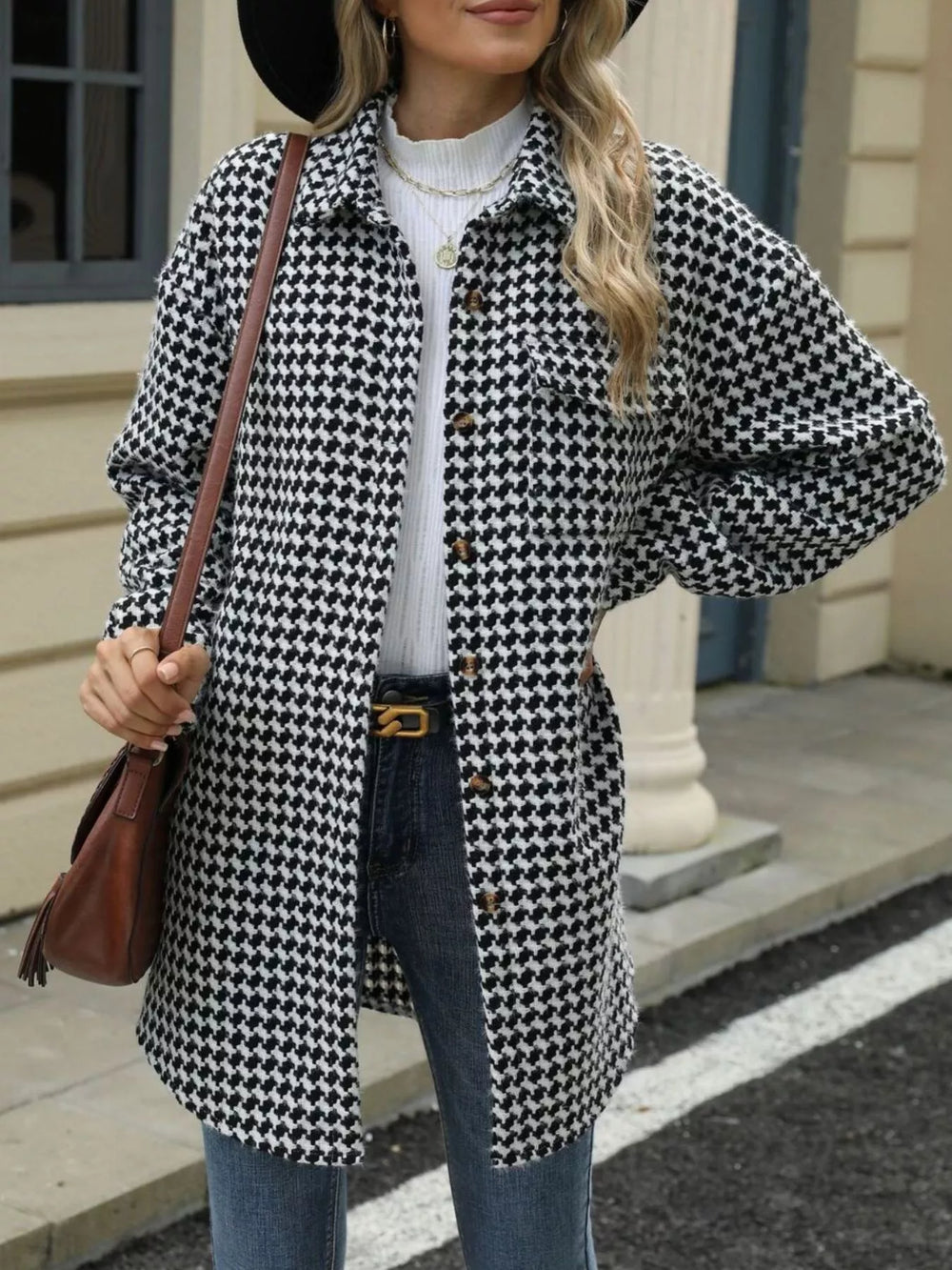 Woman wearing a houndstooth button-up long sleeve coat with a handbag, stylish street fashion.